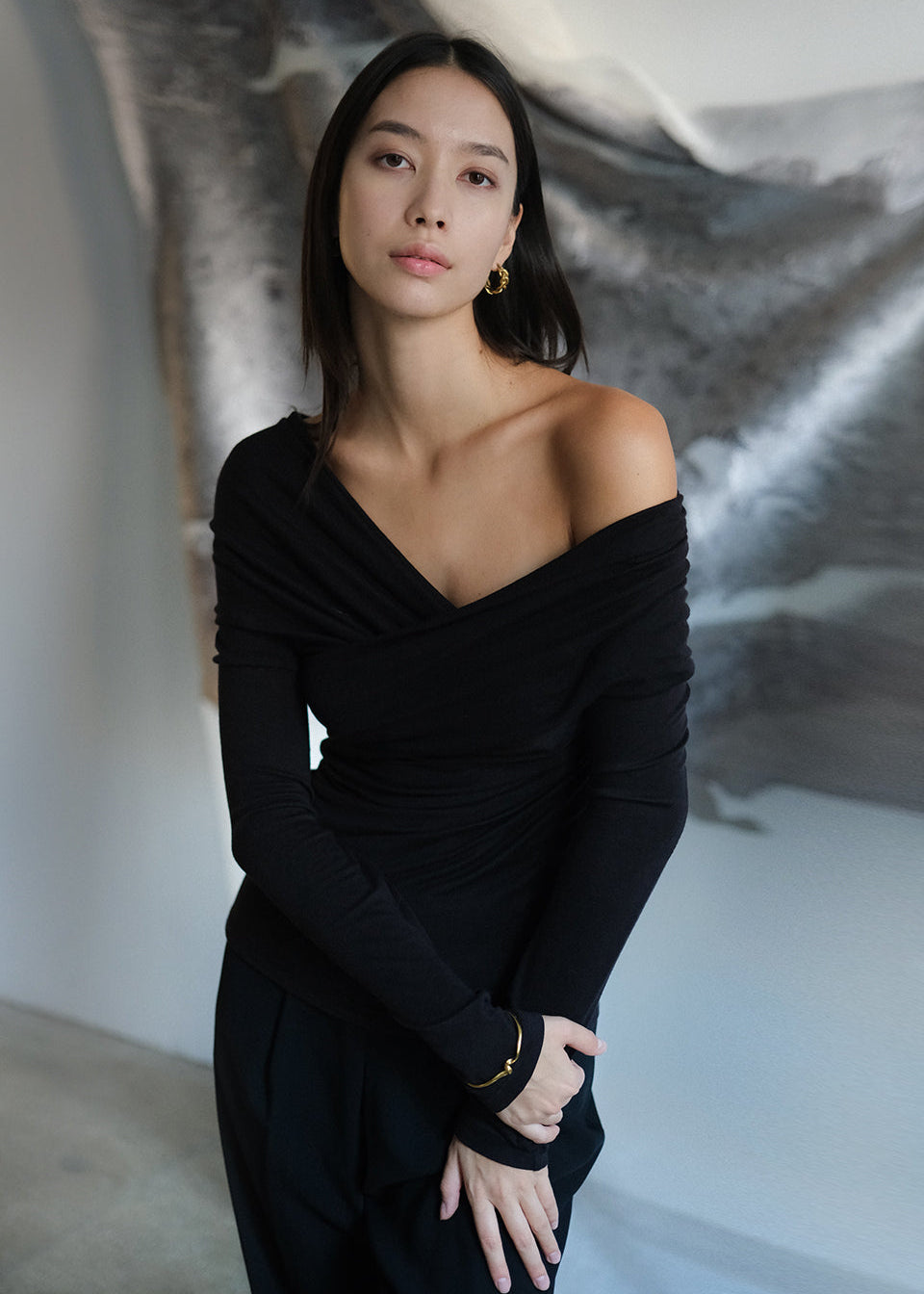 Woman wearing a black off-shoulder dress against a neutral background