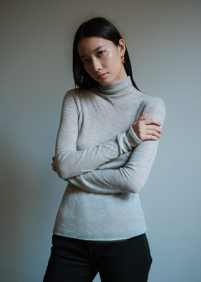 Woman wearing a light gray mock neck Italian cashmere sweater.