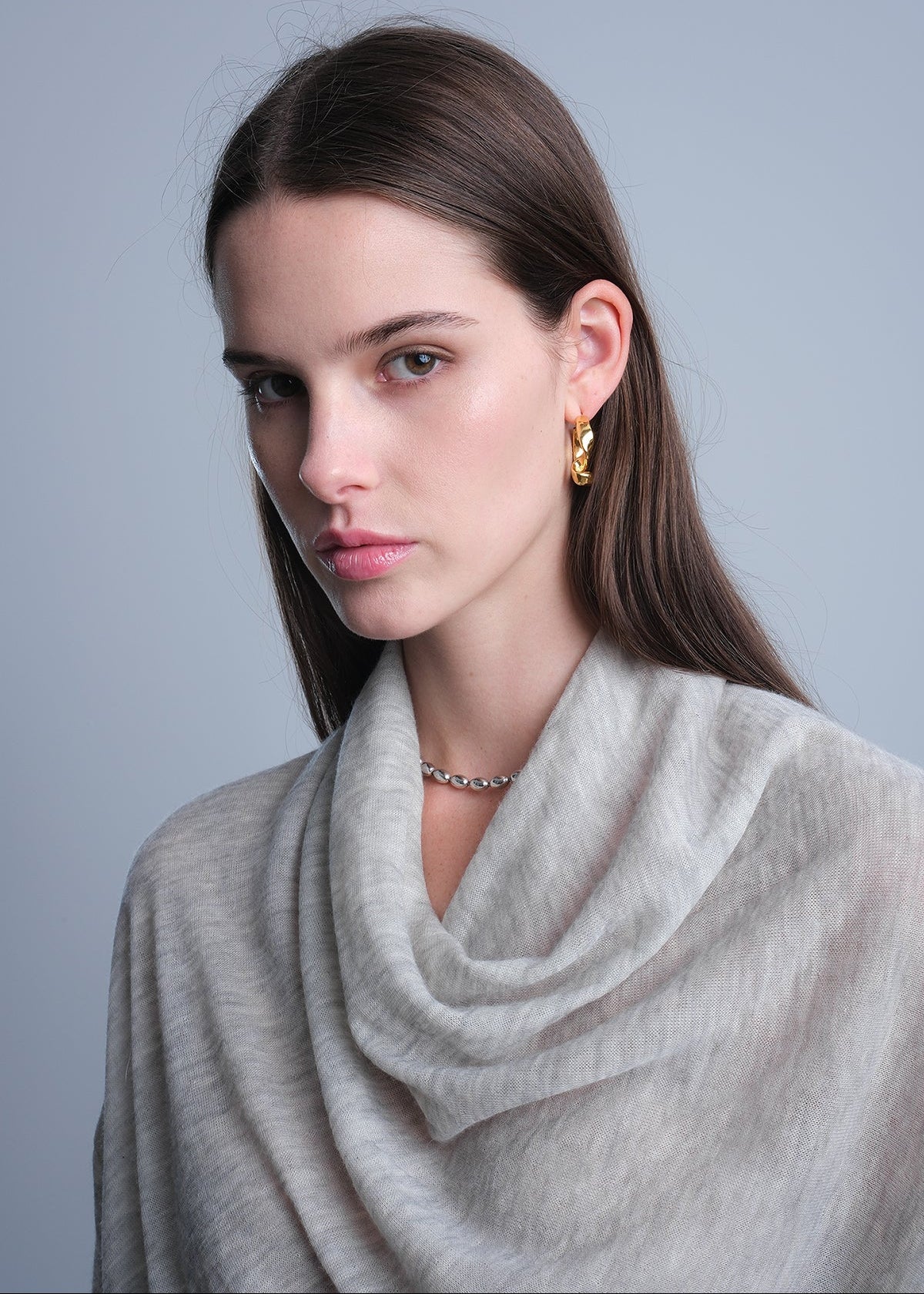 Woman wearing a light gray cashmere cowl neck sweater .