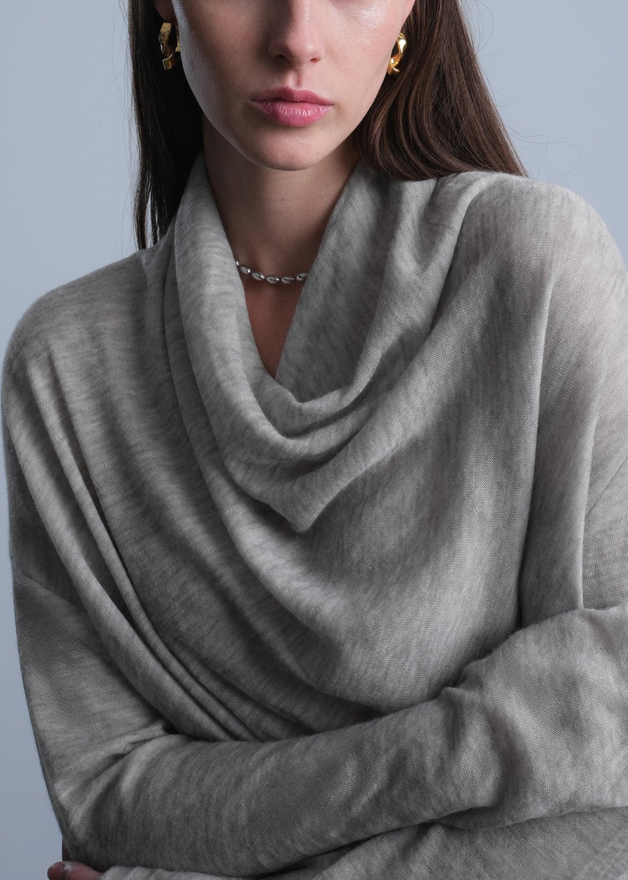 Woman wearing a gray cashmere sweater against a plain background