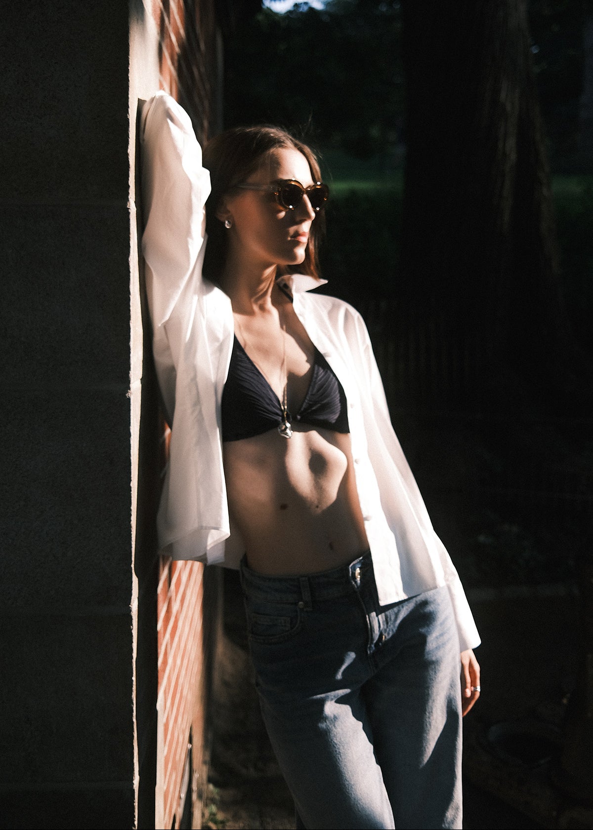 Woman wearing a jeans with a white shirt over her swimwear, white shirt as cover up