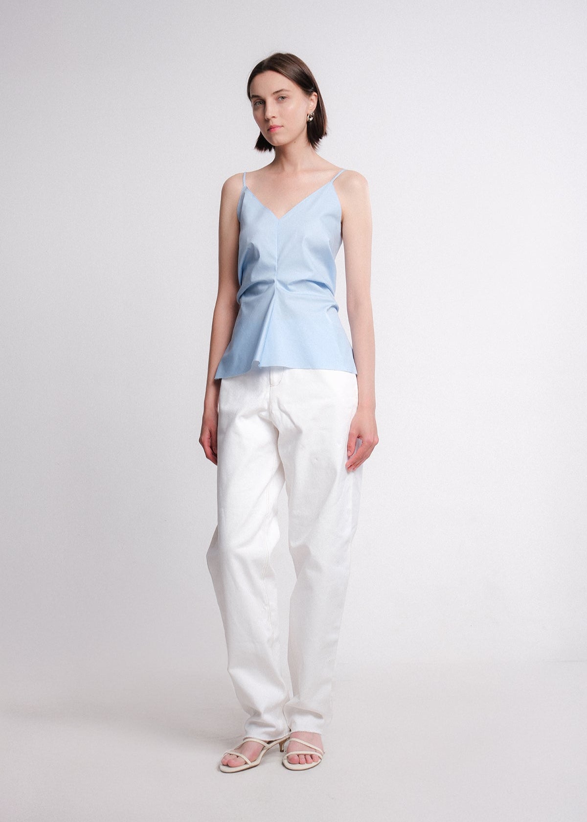 Light blue cotton poplin camisole top with thin straps, V-neckline, and front-gathered detail creating a flared hem.