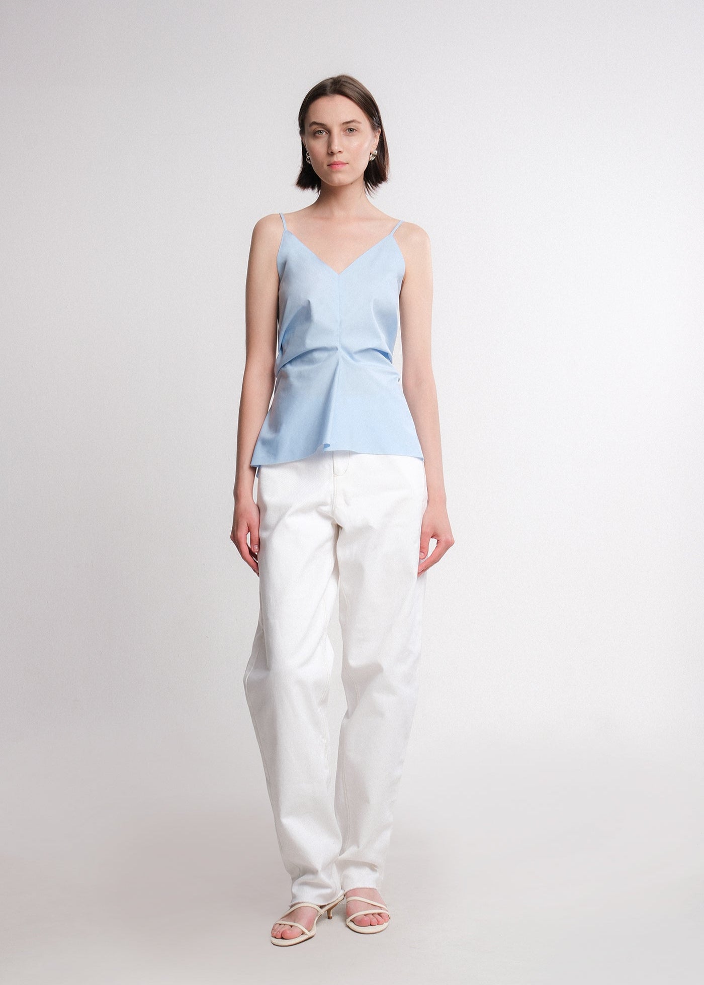 Light blue cotton poplin camisole top with thin straps, V-neckline, and front-gathered detail creating a flared hem.