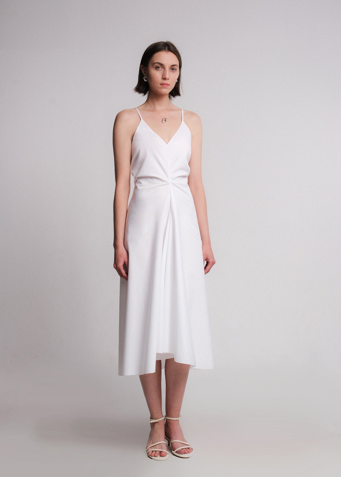 Sleeveless white midi dress made from cotton poplin, featuring a deep V-neckline, think spaghetti straps, a structured waist, and a softly flared A-line skirt.