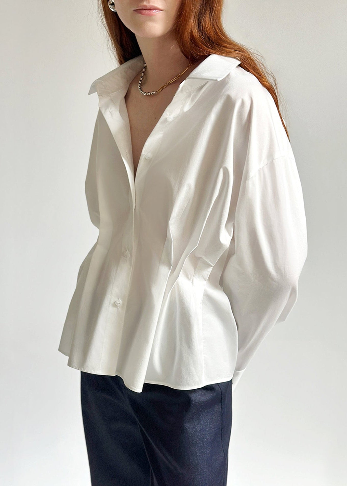 Sora Shirt – oversized white cotton shirt with pleated waist and feminine shape, by Laeir. A minimalist layering blouse for year-round wear.