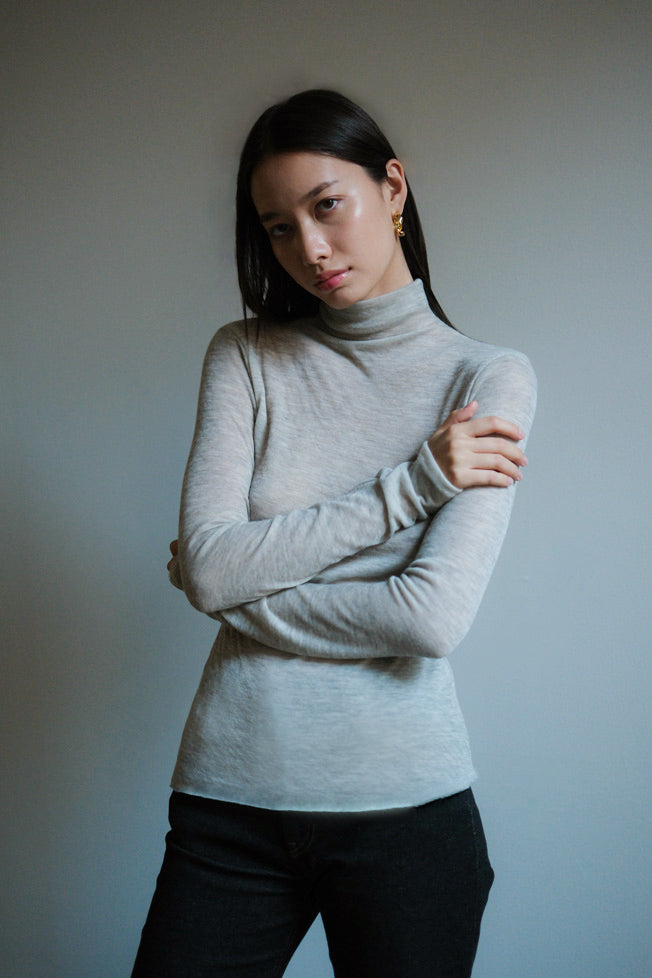 Woman wearing a light gray mock neck Italian cashmere sweater. 