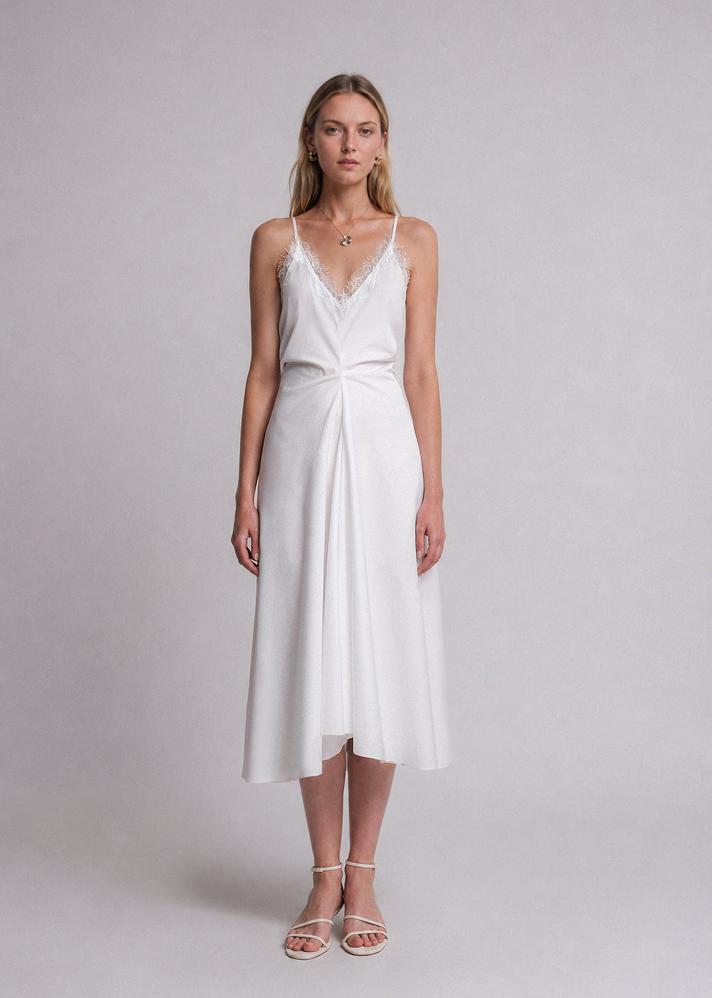 Woman wearing a white slip dress with lace detail around the neckline