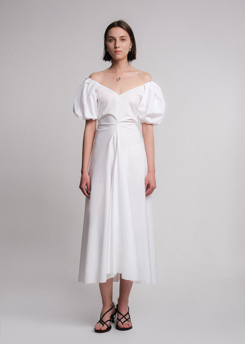 Maxi dress made of white cotton poplin fabric, featuring voluminous puff sleeves, a deep V-neckline, a gusset for added movement, and a flared A-line skirt.